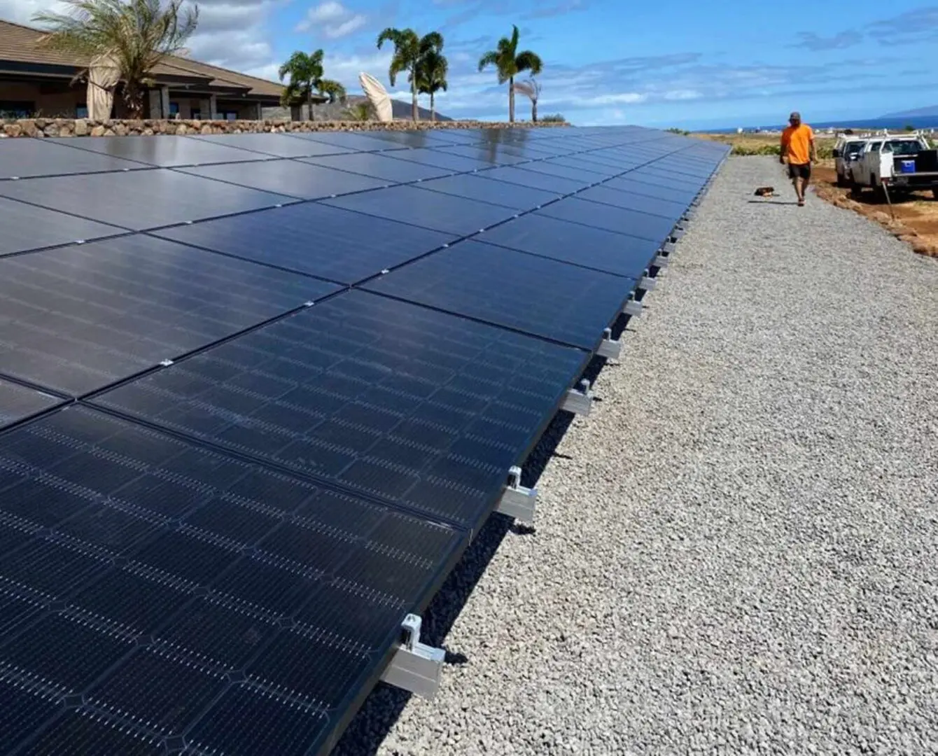 Man walking past a large array of solar panels on the roof of a house in house